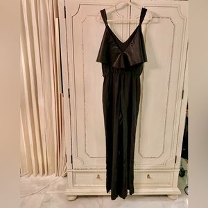 Black silk crepe jumpsuit with straps and ruffle detail at the neckline from Rio